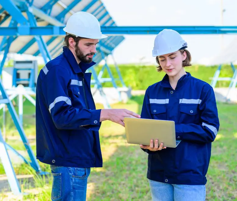 image-2 Engineers with helmets using a laptop outdoors.